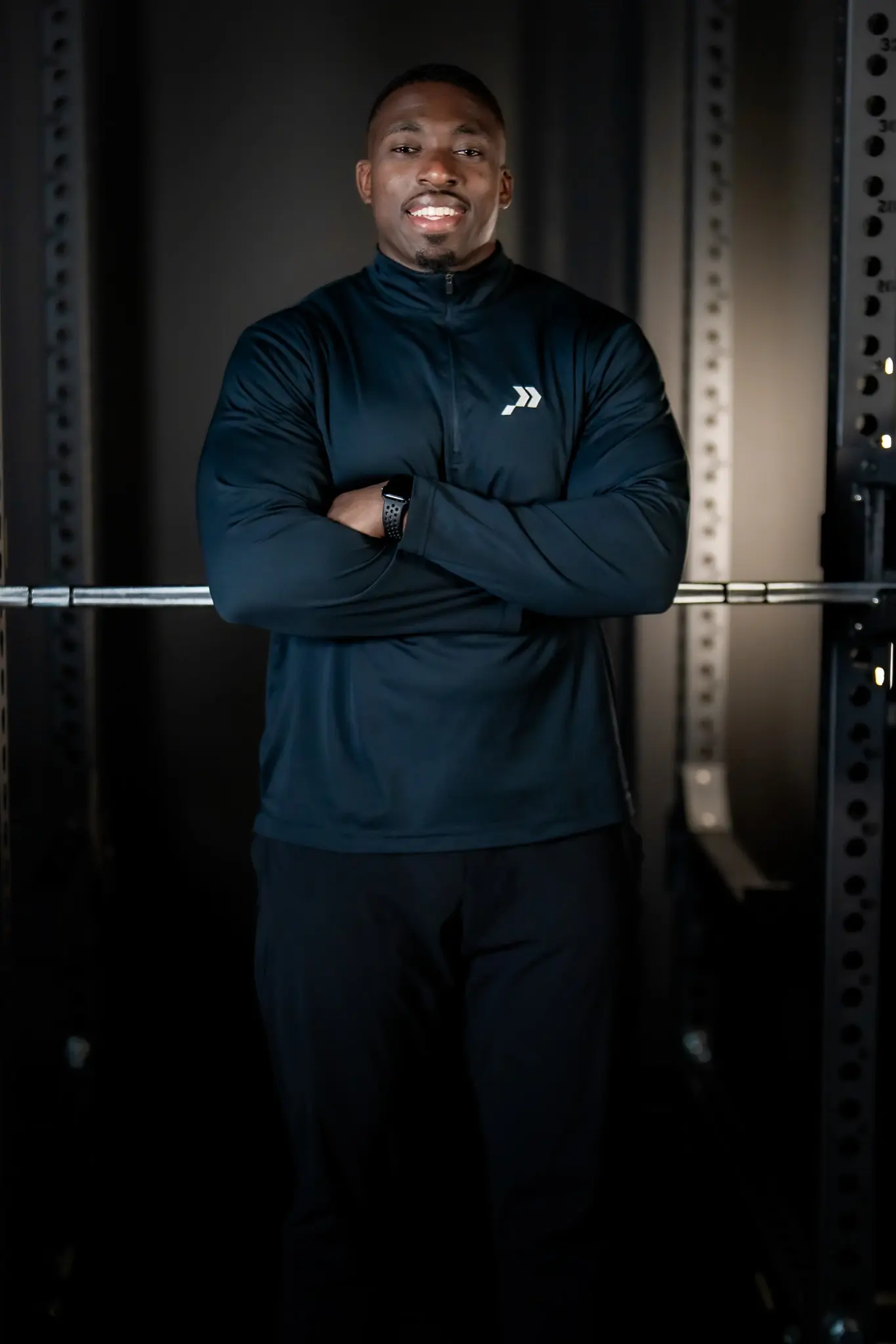 Professional portrait of the PROS owner smiling with arms crossed in front of the power rack at the Fort Lauderdale clinic